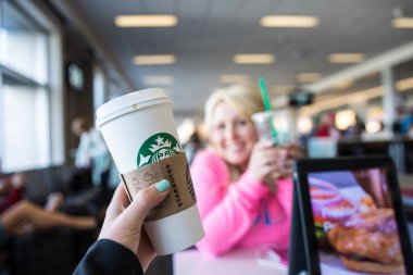 Minneapolis, Mn - 2 Mayıs 2018: El bir Havaalanı'nda bir Starbucks kahve içecek kadar tutar. Kasten Kupası üzerinde odaklanmaya bulanık arka plan. Diğer yolcuların bulanık arka planda