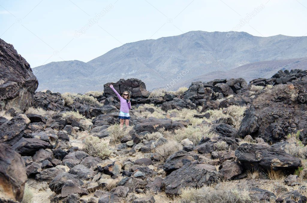 Young adult woman explores the Fossil Falls area in the Eastern Sierra Nevada Mountains of California