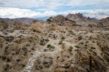 Kadın uzun yürüyüşe çıkan kimse Alabama Hills ile kir iz boyunca Mobius Arch döngü Trailhead için yürüyor
