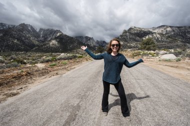 Yetişkin bir kadın, Lone Pine California 'da Whitney Portal Road 'un ortasında durmaktadır. Bu asfaltsız yol, Whitney Portal kamp kadar Alabama Hills rekreasyon alanı üzerinden gider.