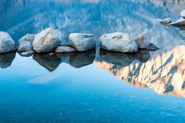 Ayrıntı soyut fotoğraf California gündoğumu, sakin bir mahkum göl kenarında Sierra Nevada dağlarının yansıması ve kayalar