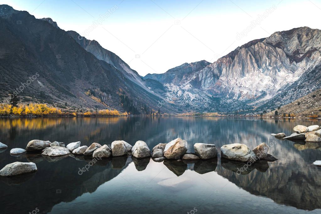 Long exposure sunrise photo of Convict Lake, an alpine lake in the Sierra nevada mountains of California, with alpenglow on the mountain peak on a fall morning