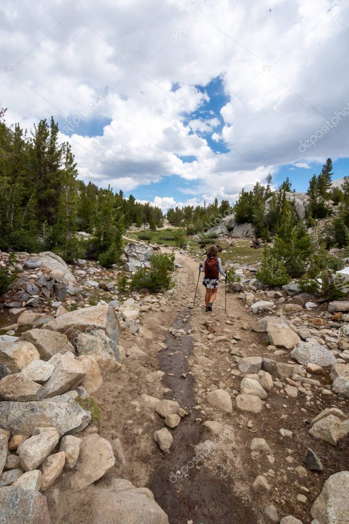 Female hiker concentrates while hiking on a dowhill slope in the Eastern Sierra Nevada mountains in the Little Lakes Valley trail