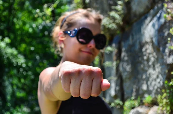 Woman with hand in a knuckle fist position.  Smug smile, defocus