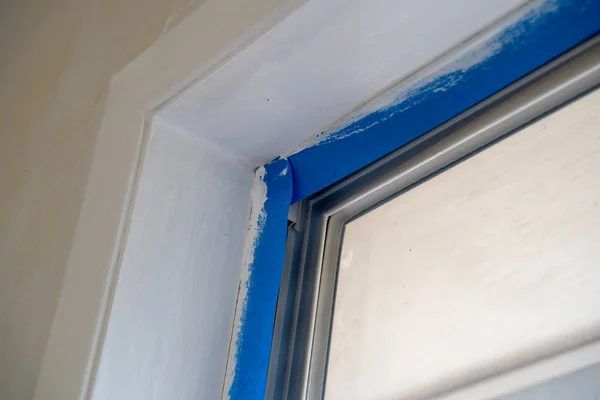 Janela guarnição coberta com fita de pintores azuis durante a casa renovati — Fotografia de Stock