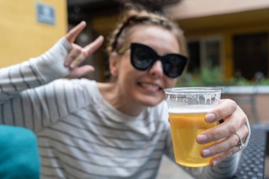 Genç kadın plastik bir bardağa bira tutuyor. Bira odaklanın, Inten