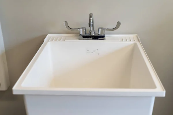 Çamaşır odasında kapalı, beyaz plastik bir lavabo.