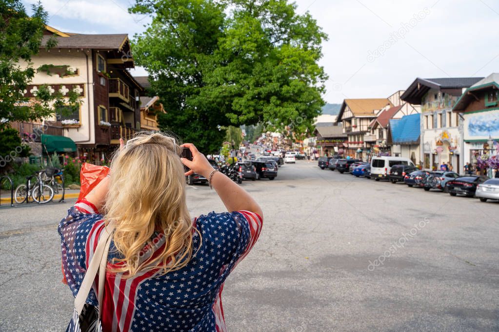 Blonde woman tourist wearing American themed USA gear takes phot