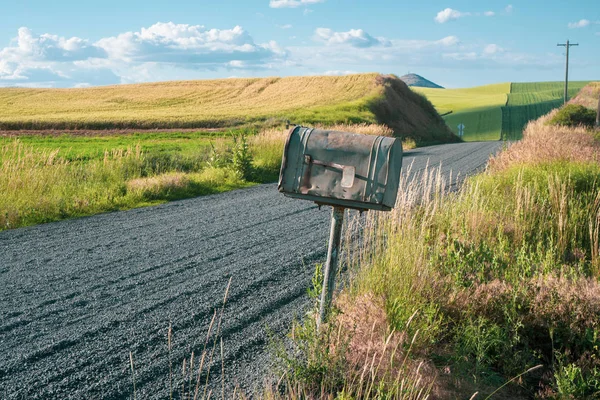 Old rusted abandoned mailbox by the side of a dirt unpaved farm — Stock Photo, Image