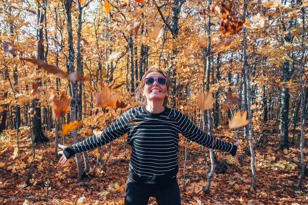 Mujer lanzando hojas de otoño en el aire, en el bosque, lleno de —  Fotos de Stock