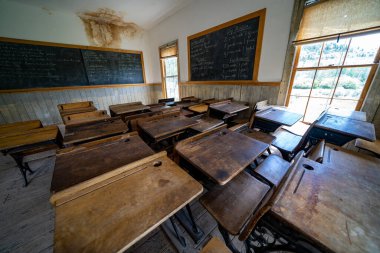 Bannack, Montana - 29 Haziran 2020: Devlet parkındaki hayalet kasabadaki eski okul binasının içinde masalar ve bir karatahta ile