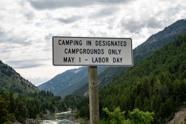 Sign in the Targhee National Forest, near Alpine Wyoming for camping in desingated campgrounds only May 1 through Labor Day (Summer) clipart