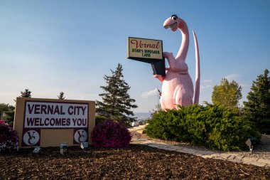 Vernal, Utah - September 24, 2020: Sign for Vernal Utah, with its famous pink dinosaur statue, taken at dusk clipart