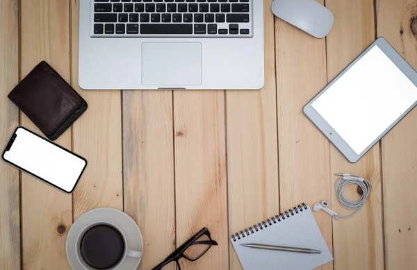 Office wood table with notepad,laptop smartphone pen mouse and coffee cup. View from above with copy space