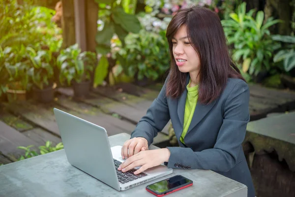 asian woman using laptop at outdoor Garden.