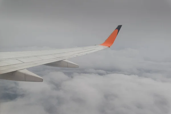 flying plane in air, partial view of airplane wing in sky