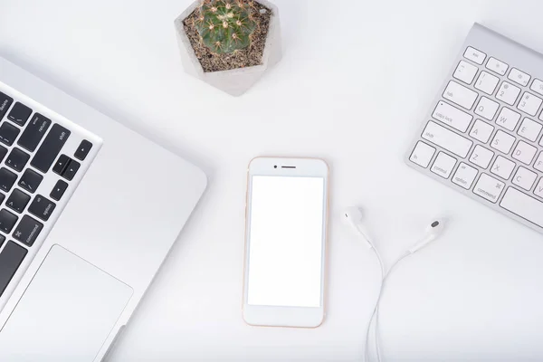 Modern white office work table with smartphone mock up laptop ,earphone and catus, top view