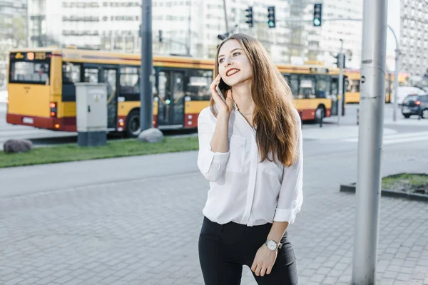 A business woman speaks through the phone. A good girl is sitting on the bench. A young woman in the city center. — Stock Photo, Image