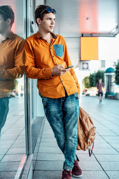 Stylishly dressed young man on the streets of Warsaw. The guy in the city center. Travel the European city. Man with a briefcase. A young man with a red screw. A young student is in a hurry to study. A man goes to work.