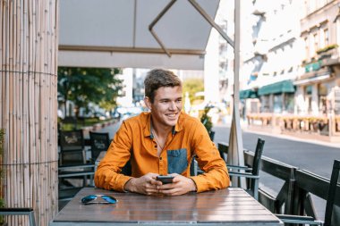 Şık giyinmiş genç adam Varşova sokaklarında. Kent merkezindeki adam. Avrupa şehir seyahat. Evrak çantalı adam. Adam tablo ve çağrıları oturuyor. Adam elini dalgalar ve hoş geldiniz.