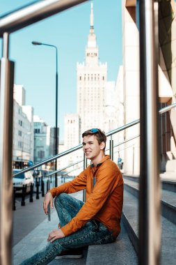 Şık giyinmiş genç adam Varşova sokaklarında. Kent merkezindeki adam. Avrupa şehir seyahat. Evrak çantalı adam. Kırmızı bir vida ile genç bir adam. Genç bir öğrenci eğitim için bir şeyin peşinde. Bir adam işe gider.