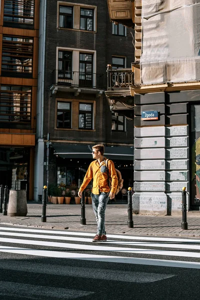 The guy crosses the street through the pedestrian crossing. Stylishly dressed man with a briefcase in a hurry to work and study. The man travels to the cities of .Europe. Poland, Warsaw.