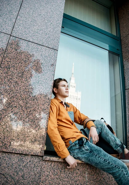 Stylishly dressed young man on the streets of Warsaw. The guy in the city center. Travel the European city. Man with a briefcase. A young man with a red screw. A young student is in a hurry to study. A man goes to work.