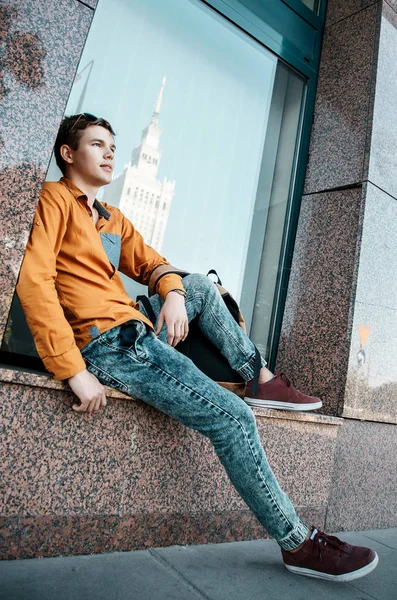 Stylishly dressed young man on the streets of Warsaw. The guy in the city center. Travel the European city. Man with a briefcase. A young man with a red screw. A young student is in a hurry to study. A man goes to work.