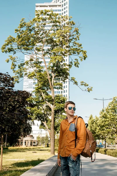 Stylishly dressed young man on the streets of Warsaw. The guy in the city center. Travel the European city. Man with a briefcase. A young man with a red screw. A young student is in a hurry to study. A man goes to work.