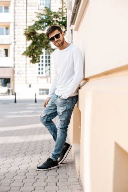 Genç bir adam şehrin sokaklarında dolaşıyor. Çocuk güneş gözlüğü şık adamın binanın yanında. Adam bir kamçı üzerinde oturur. Sakal ve saç, şık bir adamda.