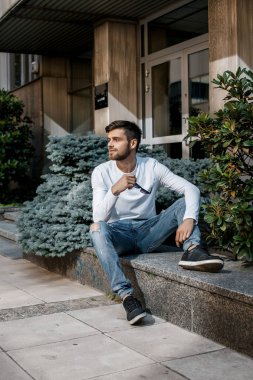 Genç bir adam şehrin sokaklarında dolaşıyor. Çocuk güneş gözlüğü şık adamın binanın yanında. Adam bir kamçı üzerinde oturur. Sakal ve saç, şık bir adamda.