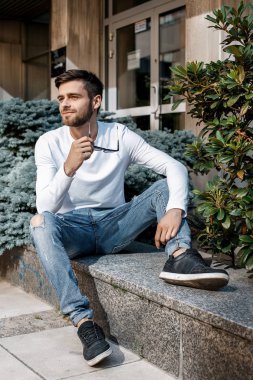 Genç bir adam şehrin sokaklarında dolaşıyor. Çocuk güneş gözlüğü şık adamın binanın yanında. Adam bir kamçı üzerinde oturur. Sakal ve saç, şık bir adamda.