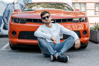 Genç bir adam şehrin sokaklarında dolaşıyor. Çocuk güneş gözlüğü şık adamın binanın yanında. Adam bir kamçı üzerinde oturur. Sakal ve saç, şık bir adamda.