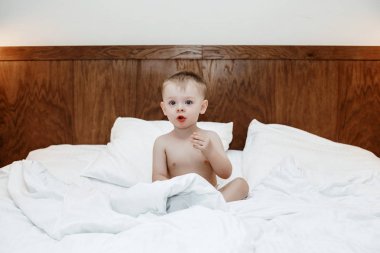 Yatakta çocuktur. Çocuk bir battaniye ve yastık arasında büyük bir yatakta. Küçük bir bebek yatakta oturma ve yemek. Düşkünlük çocuk.