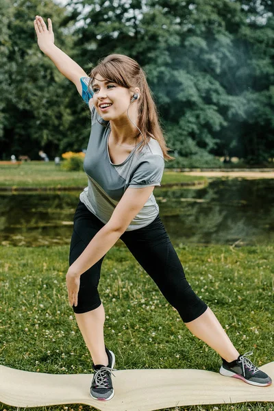 Young sports woman stretching legs on the stairs in the modern city. Healthy lifestyle in the big city. Sports woman relaxing listening to the music during the morning exercise outdoors. sports woman stretching in the park during the morning exesrcis