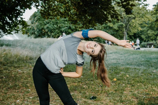 Young sports woman stretching legs on the stairs in the modern city. Healthy lifestyle in the big city. Sports woman relaxing listening to the music during the morning exercise outdoors. sports woman stretching in the park during the morning exesrcis