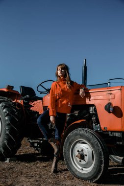 Genç bir kadın mısırın yanında. Köydeki güzel kız. Kırmızı traktörün yanındaki kız. Tarım makineleri.
