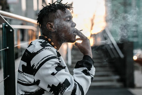 Палити хлопця. Молодий африканський чоловік палить на сонячній вулиці міста — стокове фото