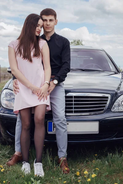 Bonito jovem casal perto do carro. O cara e a menina estão apaixonados. Família e seu carro. — Fotografia de Stock