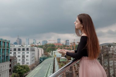 Denizin kayalık kıyısında duran bir kadın. Korkuluklara yaslanan bir kız. Başka tarafa bakıyor. Önüne bak. Yalnız, genç, yetişkin bir insanın arka görüntüsü. Güzel bir deniz manzarası. Mavi gökyüzü.