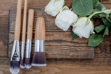 Ahşap bir arka planda kozmetik kemikler. Kozmetik fırçalar ve beyaz çiçekler.