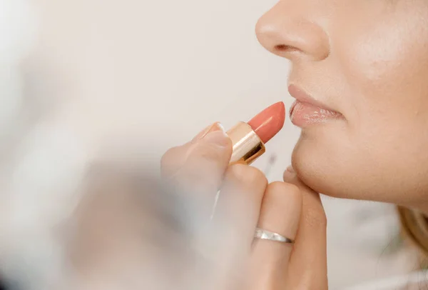 Makeup. Painting lips with lipstick. Applying makeup on a woman\'s face. Drawing lipstick with a bone.