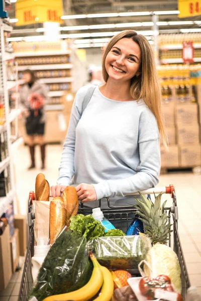 Woman with full trolley at the supermarket.