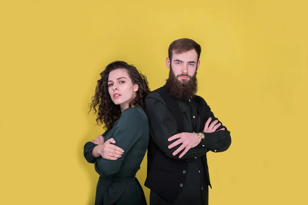 Couple standing back to back on yellow background.