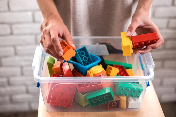 Woman\'s hands putting colored blocks into box.