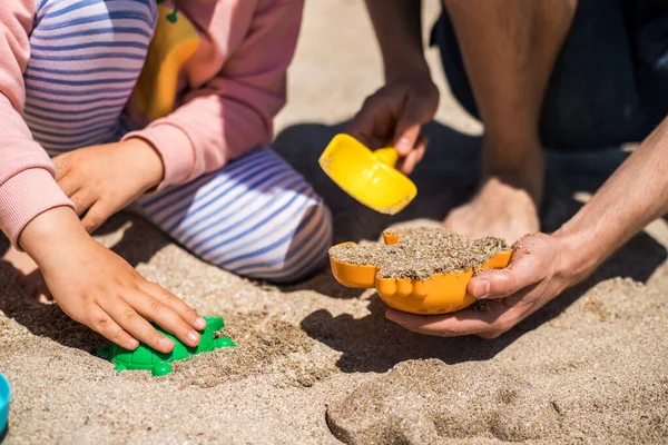 Happy father and daughter play in sand on the beach and have fun together.