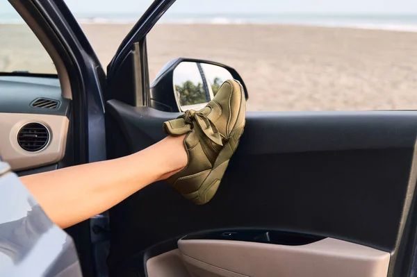 Sahildeki arabanın camından kadın ayağının yakın plan fotoğrafı.