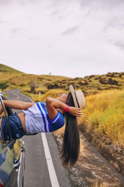 Arabanın camında oturmuş şapkasını takmış mutlu bir genç kadın seyahatin tadını çıkarıyor ve eğleniyor.