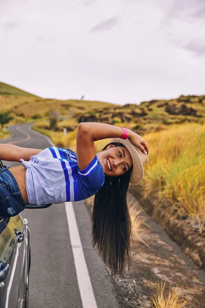 Arabanın camında oturmuş şapkasını takmış mutlu bir genç kadın seyahatin tadını çıkarıyor ve eğleniyor.