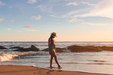 Sahilde dalgaların arasında duran genç bir kadın.